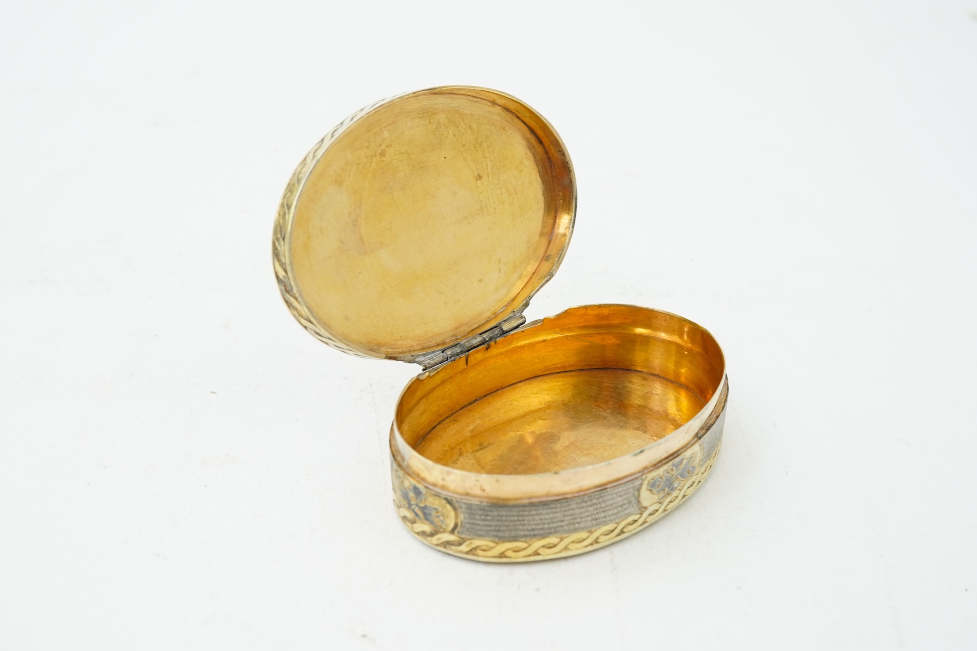 A 19th century Swiss? parcel gilt white metal oval snuff box with hinged cover